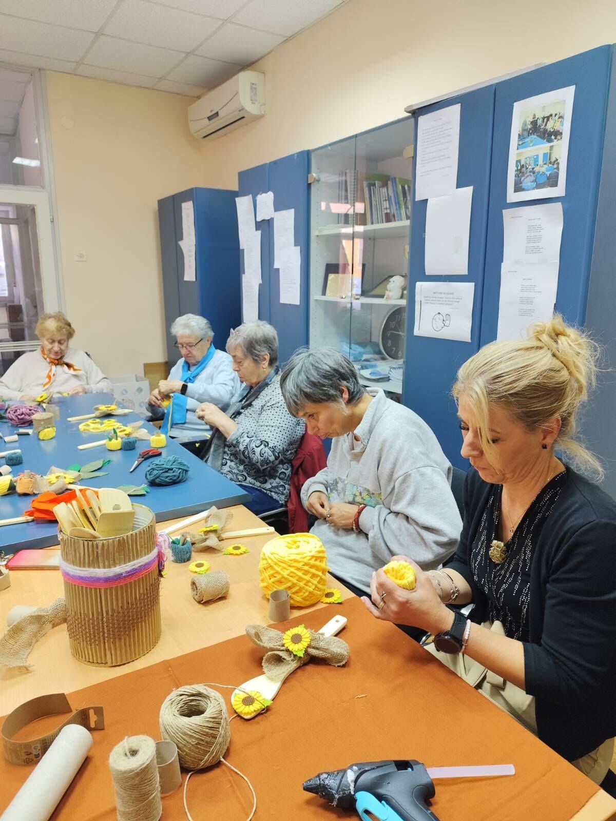 Members making handmade decorations with twine and paper at a shared workshop table